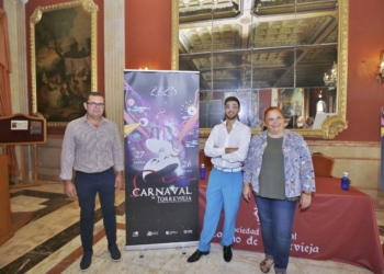 El presidente de la Asociación Cultural Carnaval de Torrevieja, Francisco Pizana; el autor del cartel anunciador, Damián Bear, y la concejala de Fiestas, Concha Sala, junto al cartel de la próxima edición del carnaval | Joaquín Carrión