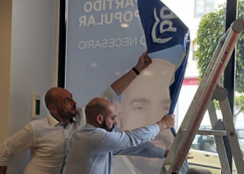 Carlos Pastor, de azul, arrancando su propia cartelería de la que iba a ser su sede electoral.